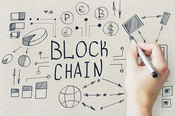 Mão escreve blockchain e desenha criptomoedas