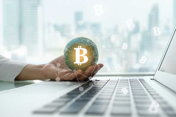 Mão feminina segurando uma das criptomoedas.